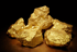 Mehrere goldene Nuggets oder Goldbrocken auf schwarzem Hintergrund.