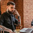 Tätowierter Mann im Gespräch am Telefon mit Laptop – Symbolbild für strategisches Performance Marketing in der Tattoo-Branche