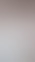 Kosmetikerin in weißem Kittel und blauen Handschuhen massiert das Gesicht einer Kundin, die auf einer Liege liegt.