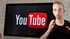 Ein Mann in einem schwarzen T-Shirt steht vor einem Monitor mit dem YouTube-Logo.