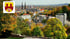 Blick über das herbstliche Bielefeld mit dem Stadtwappen, der Neustädter Marienkirche und bunten Bäumen.