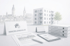 Immobilienmakler-Schreibtisch mit Exposé, Tablet und Aktenordnern vor einem modernen Wohnhaus und Stadtpanorama.