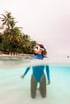 Halb über, halb unter Wasser: eine Person mit Taucherbrille vor Palmen