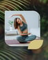 A fit woman in athletic wear doing a seated side stretch on a yoga mat.