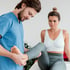 Physical therapist examines a female patient's knee and foot.