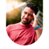A man in a red shirt winces and holds his temple, appearing to have a headache or migraine.