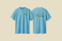 Zwei blaue T-Shirts: Eines mit kleinem Logo „Kindertagesstätte Sonnenblume“ auf der Brust, eines mit großem Logo auf dem Rücken.