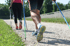 Zwei Personen Nordic Walking auf einem Schotterweg, von hinten gesehen, mit Wanderstöcken.