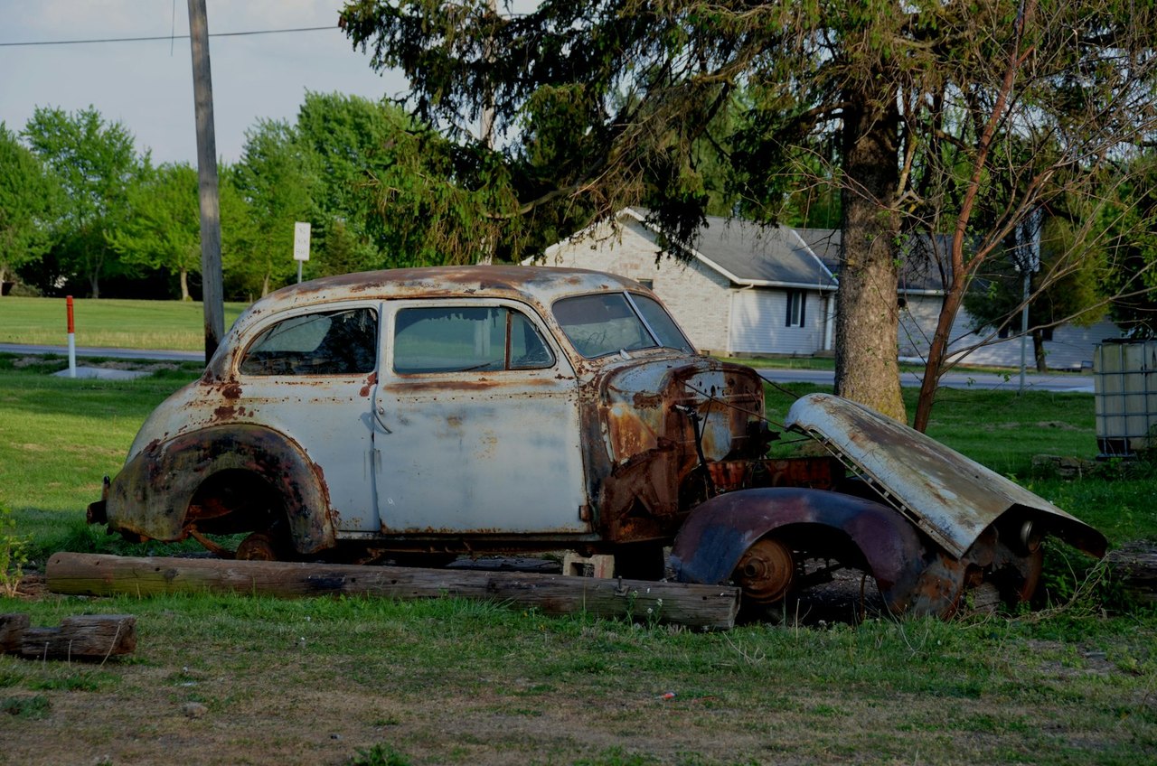 Rusted abandoned vehicle sitting in a grassy yard, the kind that raises abandoned vehicle Florida questions for neighbors