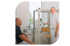 Arzt lächelt und zeigt auf Lungenfunktionstestgerät, während Patient auf Stuhl sitzt.