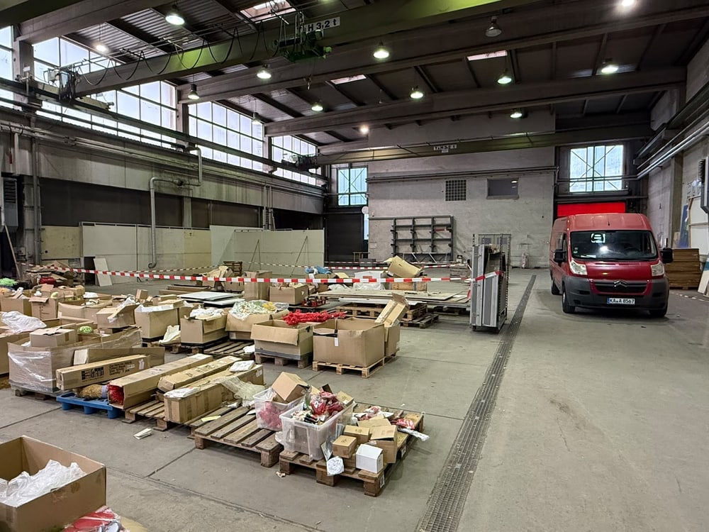 Gewerbehalle während der Räumung, Waren auf Paletten sortiert