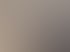 Ein heller Raum mit Holzboden, einem Einzelbett, einem Sofa, einem TV und einer offenen Balkontür, die auf einen Balkon führt.