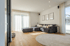 Modernes Wohnzimmer mit großem Ecksofa, hellem Holzboden, runder Teppich und großen Fenstern.