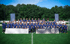 Eine große Gruppe junger Fußballspieler in blauen Trikots steht auf einem Fußballfeld vor Bäumen und Bannern mit "BUFFON FOOTBALL ACADEMY".