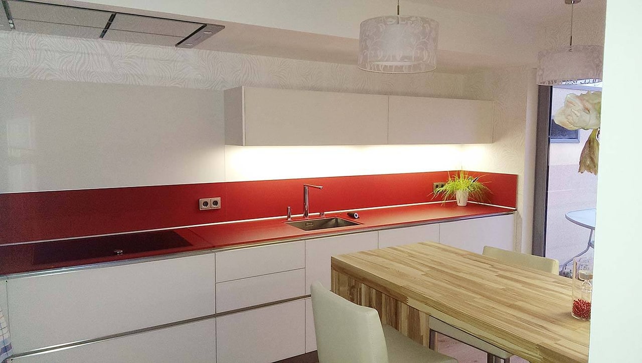 Küche mit roter Glasrückwand und Holztisch