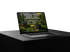 Laptop mit geöffneter Website, die winzige Häuser in einer grünen Landschaft zeigt und den Text "Entdecken Sie kompakte Wohnlösungen" anzeigt.