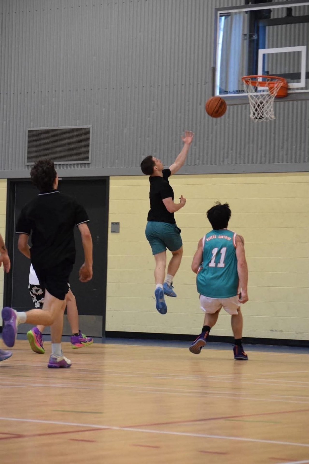 Un joueur de basketball saute pour un tir pendant que le ballon touche l'arceau
