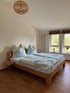 Ein Schlafzimmer mit einem Holzbett, zwei Kopfkissen, zwei Decken und zwei kleinen roten Nachttischlampen.