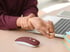 Person clutching a painful wrist while using a computer mouse, a sign of tendon strain.