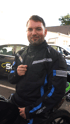 Mann in schwarzer und blauer Motorradjacke sitzt auf einem Motorrad.