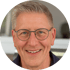 Ein lächelnder Mann mittleren Alters mit Brille und kurzen grauen Haaren.
