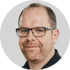 Ein lächelnder Mann mit Brille und kurzem Haar blickt direkt in die Kamera.