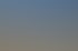 Eine Gruppe von zehn Personen geht auf einem gepflasterten Weg vor einem gelben Gebäude und blauem Himmel.