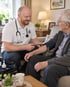 Arzt misst bei einem älteren Patienten zu Hause den Blutdruck