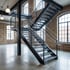 Moderne schwarze Metalltreppe in einem Loft mit Backsteinwänden und großen Fenstern.