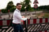 Christian Roßmann entspannt und lächelnd auf einem E-Roller an einer Baustelle.