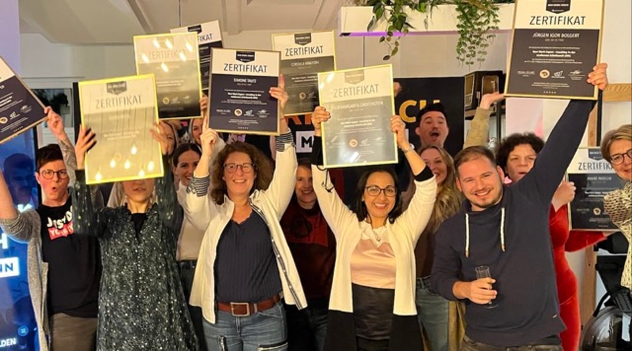 Gruppe feiert mit erhobenen Zertifikaten den Abschluss eines Workshops in der NEOP Academy