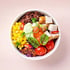 Eine bunte Poke Bowl mit Huhn, Reis, Mais, Kirschtomaten, Rotkohl, Avocado und Chilis.
