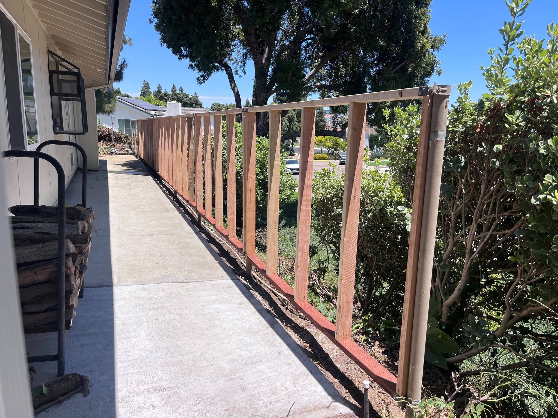 Perimeter fence framing beside a San Diego home before Hardie panel installation