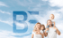 Glückliche Familie mit zwei Kindern vor einem blauen Himmel mit weißen Wolken und einem großen, transparenten "BE"-Logo.