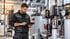 Heizungsmonteur in Arbeitskleidung bedient ein Tablet vor einer modernen Heizungsanlage mit Rohren und Kesseln.