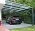Schwarzer Ford Focus unter einem modernen anthrazitfarbenen Carport mit transparentem Dach auf einer grauen Pflasterauffahrt.
