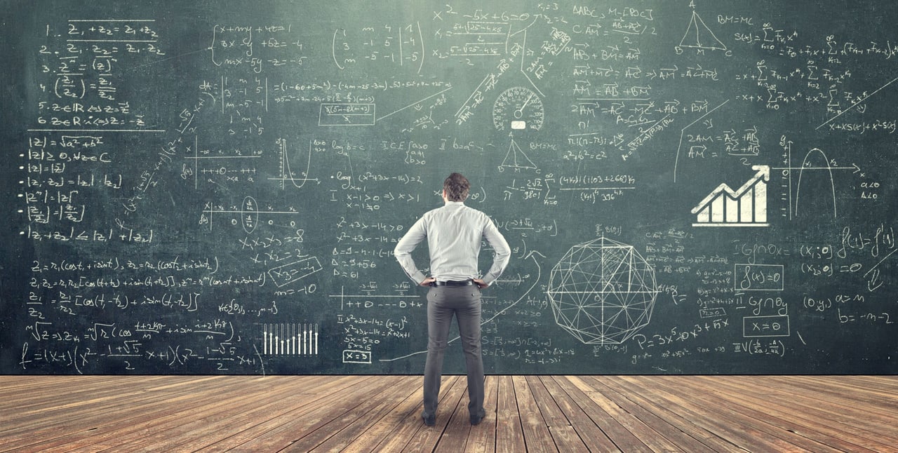 Mann in weißem Hemd steht vor einer grünen Tafel voller mathematischer Formeln, Diagramme und einem Balkendiagramm