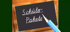 Eine Schultafel mit der Aufschrift „Schüler-Pakete“ und einem Bleistift.