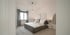 Modernes Schlafzimmer in Weiß und Grau mit Doppelbett, Nachttischlampen, Fenster mit Vorhängen und hellem Holzboden.