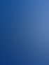 Ein Betonring wird von einem Kranarm mit Seilen gegen den blauen Himmel gehoben, die Sonne scheint von rechts.