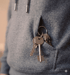 Silver keys on a ring hanging from the pocket of a gray hooded sweatshirt.