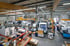 Große Produktionshalle mit zahlreichen CNC-Maschinen, Förderbändern und Werkbänken, alles in einem industriellen Umfeld.
