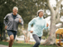 Smiling mature couple jogging in a park after Wellness Consultation.