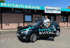 Ein Mann steigt aus einem schwarzen Auto mit "PHYSIO & VITAL"-Logo vor einem Gebäude mit "PHYSIOTHERAPIE"-Schild.