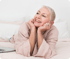 Happy mature woman relaxing on bed with a smile, symbolizing the benefits of stress relief and wellness through personalized lifestyle support.