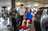 Ein Fitnesstrainer betreut einen Mann beim Training an einer Beinstrecker-Maschine im Fitnessstudio.