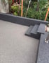 Terrasse aus hellem Steinteppich mit dunklen Treppenstufen und Mauern.