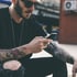 Tattoo-Influencer filmt sich bei der Arbeit mit Smartphone – darüber der Titel: 'Influencer Marketing 2024 – Chancen & Risiken für Tattoo Studios