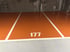 Leere orangefarbene Parklücke Nummer 177 in einer Tiefgarage mit weißen Linien.
