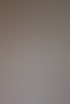 Porträt einer Frau im weißen Kittel mit verschränkten Armen vor einer Wand mit dem Schriftzug nakedda.